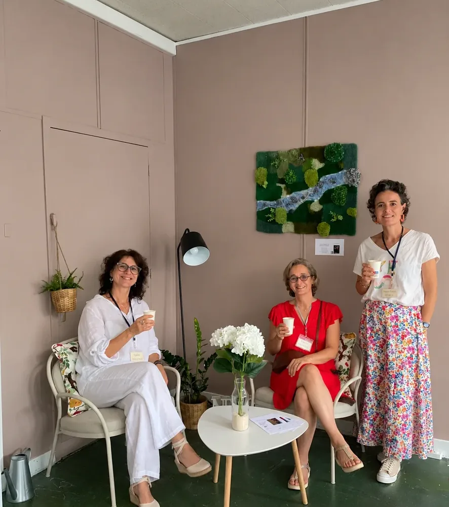 Trois personnes avec un café à la main dans un coin salon aménagé