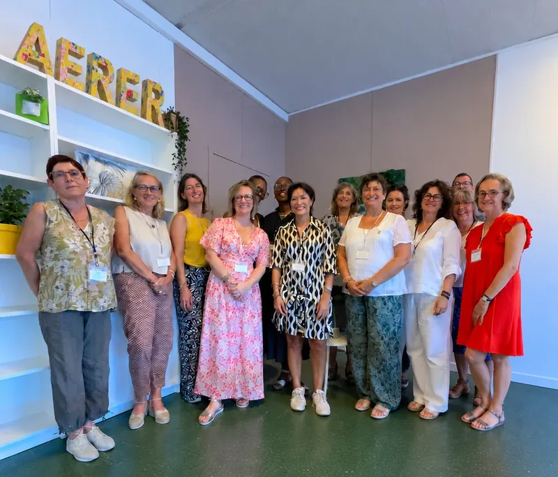 Photo de groupe : une quinzaine de participants réunis et souriants devant des étagères blanches